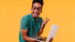 handsome-male-freelancer-glasses-smiling-ecstatic-african-student-holding-laptop-expressing-happiness